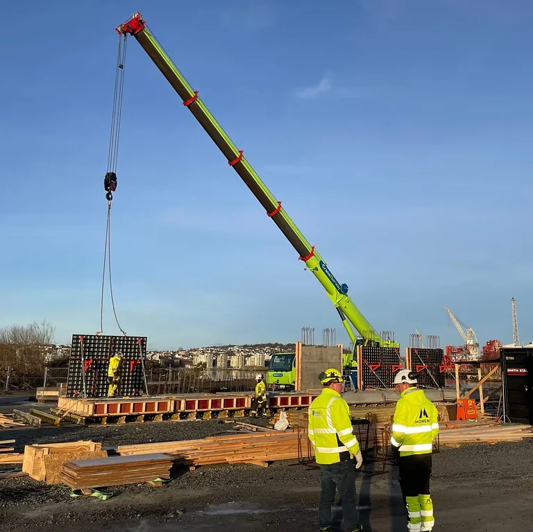 Betongelement løftes på plass av stor kranbil